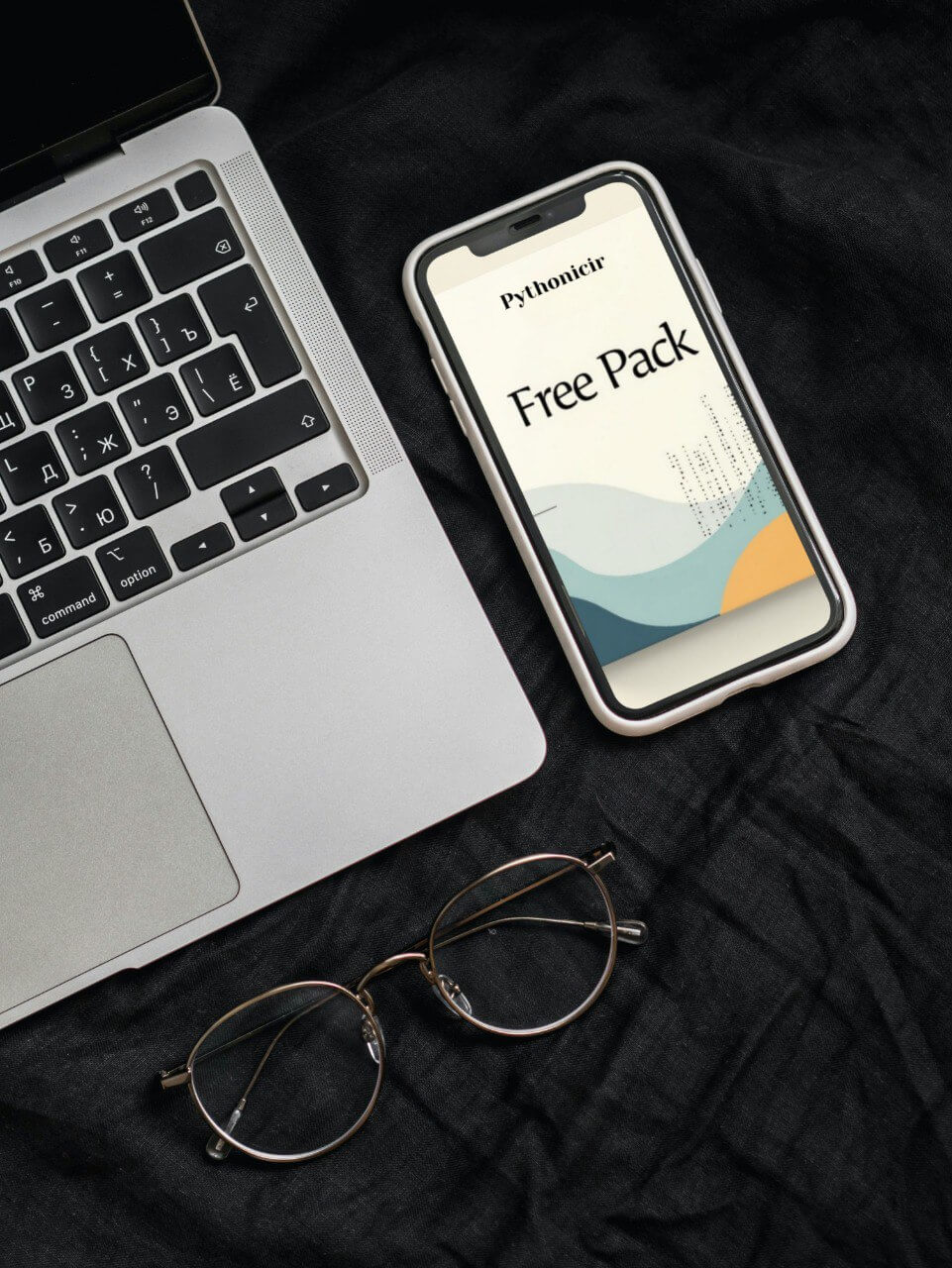 Phone with a 'Free Pack' course on screen on a laptop and eyeglasses on a dark surface