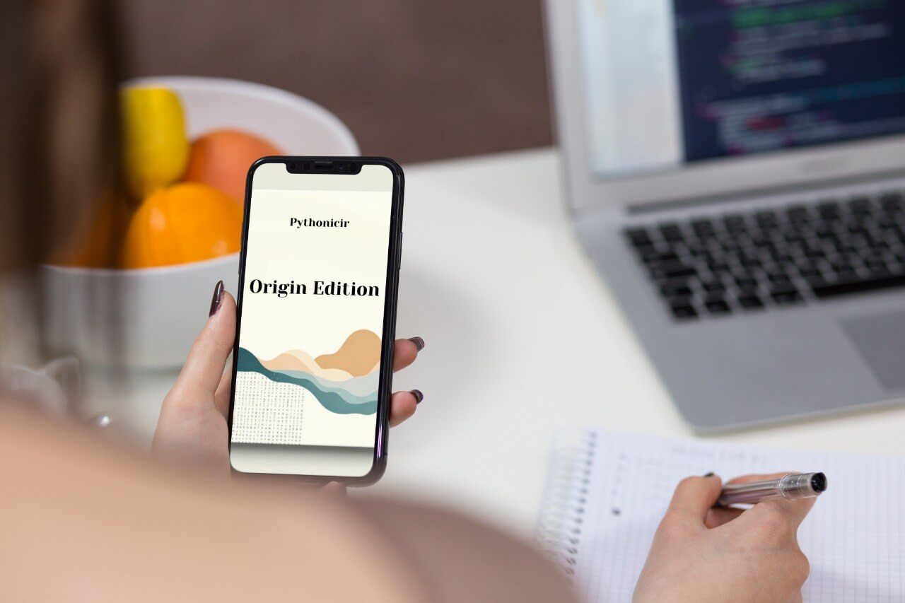 Person holding a phone with 'Pythonicir Origin Edition' course displayed, with a laptop and fruit bowl in the background.